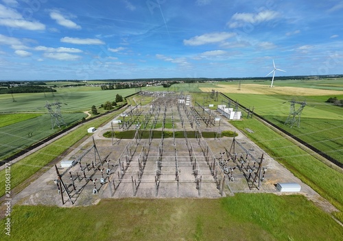 Petite centrale électrique rurale en Meurthe-et-Moselle. Vue aérienne panoramique des installations électriques, transformateurs, pylônes, câbles, répartiteurs. Au milieu des champs et des cultures.