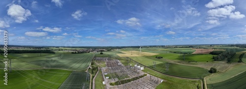 Petite centrale électrique rurale en Meurthe-et-Moselle. Vue aérienne panoramique des installations électriques, transformateurs, pylônes, câbles, répartiteurs. Au milieu des champs et des cultures.