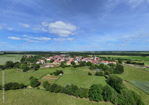 Vue aérienne panoramique du village de Laix, en Meurthe-et-Moselle, Lorraine. La commune rurale avec ses habitations et ses bâtiments entourée de champs et de cultures. Ciel bleu et nuages
