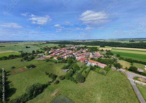 Vue aérienne panoramique du village de Laix, en Meurthe-et-Moselle, Lorraine. La commune rurale avec ses habitations et ses bâtiments entourée de champs et de cultures. Ciel bleu et nuages