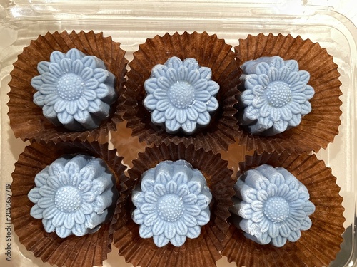 op view of blue Sampanni flower-shaped cookies in paper cups inside a container