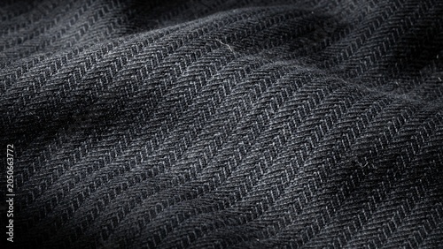 Detailed macro view of dark grey herringbone patterned fabric texture with subtle shine