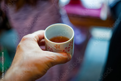 Hand holding small cup of Japanese tea in cafe