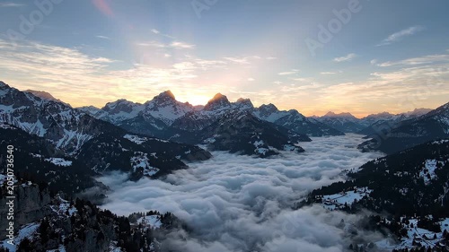 Majestic mountain landscape at sunrise with snow-covered peaks and a sea of clouds filling the valley below, creating a breathtaking natural scene in the Alps