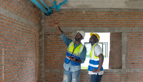 Konstfotografi Two construction worker in safety vest and hardhat inspect electrical system and water pipe, especially for security purpose