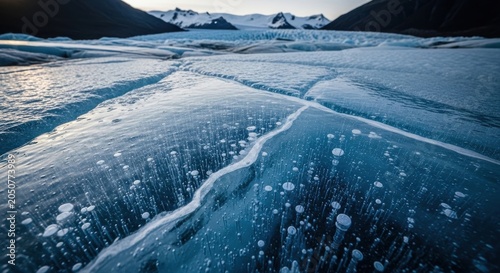 Cracked glacial ice surface with bubbles and mountain backdrop
