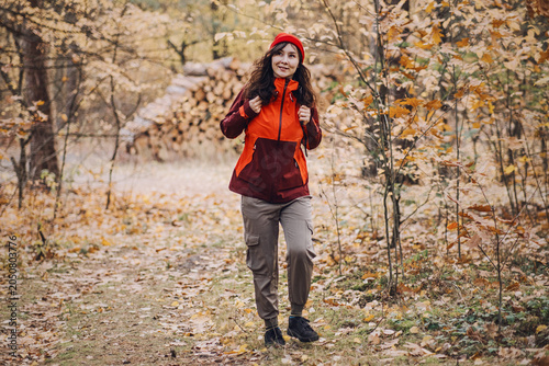 Bild auf Leinwand Woman hikes on trail in autumn forest past stacked logs