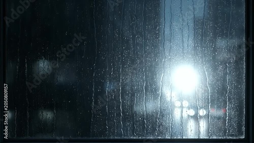 Dark Window Pane with Rain Streaks and Blurred City Lights at Night