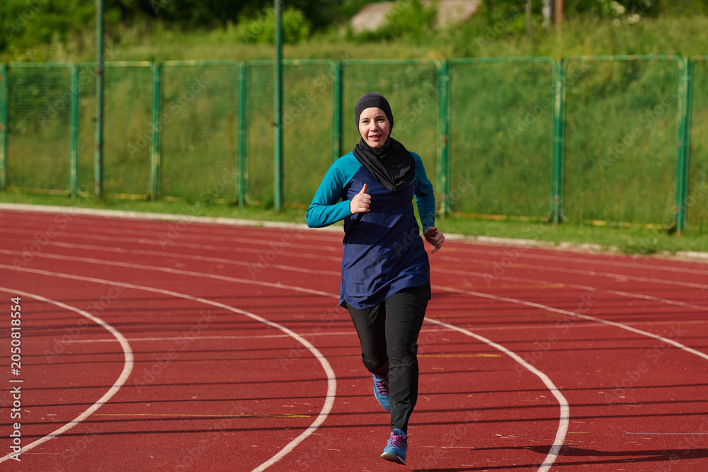 Obraz premium Muslim Woman Running on Outdoor Track in Hijab Showing Fitness, Determination and Active Lifestyle