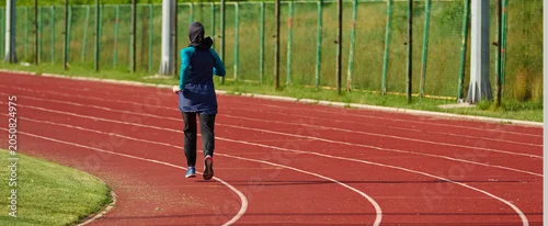 Panel kuchenny z motywem Young Woman Running on Outdoor Track Wearing Hijab and Modest Sportswear for Fitness Training