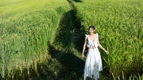 Obraz na plátně Aerial view asian woman walking in green rice field, asian woman walking on a rice field enjoy her time in nature, Travel and lifestyle asian woman walking in cascade rice fields, Northern Thailand