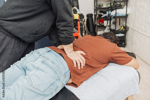 Принти на полотні Chiropractor performs a lower back adjustment on a middle aged male patient to improve spinal alignment, mobility, and pain relief