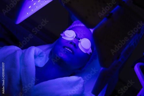 Woman undergoing blue light therapy treatment in a wellness center