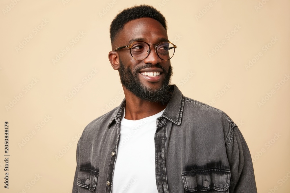 Obraz premium The Smiling Young Man Wearing Glasses in a Casual Denim Shirt Looking Away