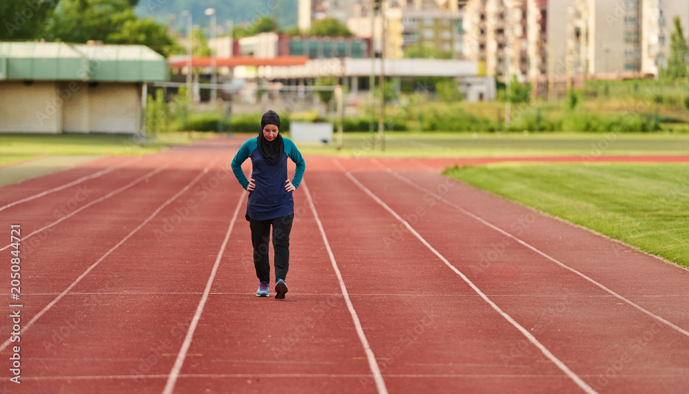 Fototapeta premium Muslim Woman Jogging on Outdoor Running Track Wearing Hijab and Sportswear for Fitness