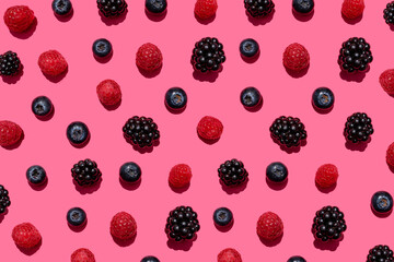 Pattern of raspberries, blueberries and blackberries against pink background