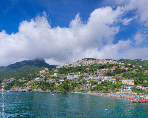 View of the Amalfi Coast from the sea, southern Italy: townscape of Raito perched on the hill with sandy beach on water's edge.