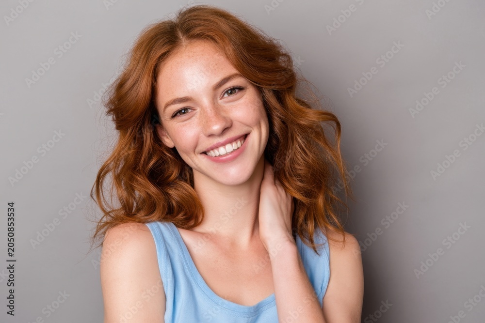 Naklejka premium The smiling woman with red hair posing confidently in a studio portrait with gray background
