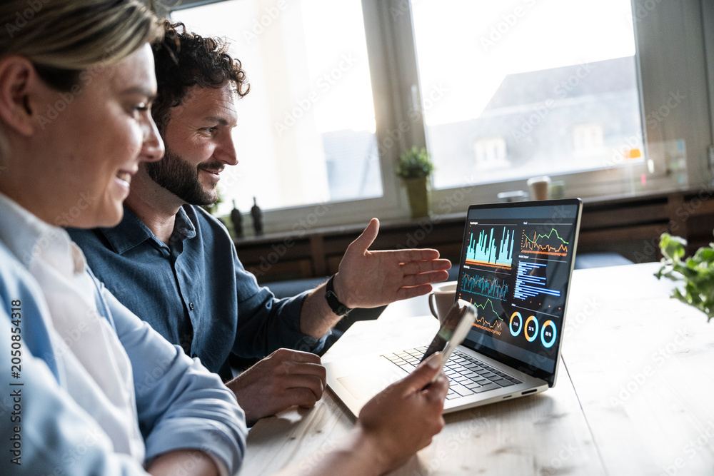 © Westend61 - Business team analyzing financial data on laptop in office