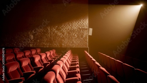 Empty luxury cinema theater with projector light beam and red velvet seats