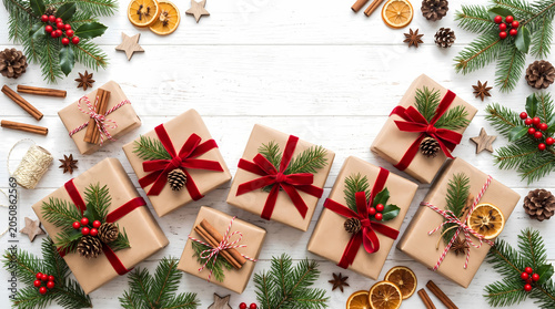 Beautifully wrapped christmas gift boxes decorated with red velvet ribbons and natural festive elements like dried orange slices cinnamon sticks pine cones and holly leaves on a bright wooden