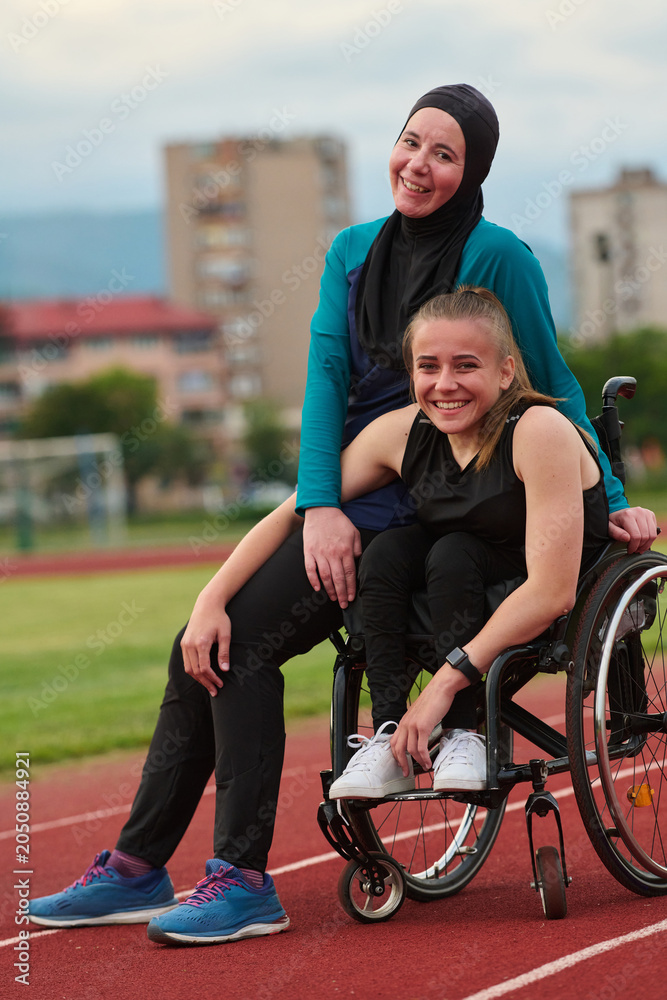 Obraz premium Smiling Female Wheelchair Athlete With Friend On Running Track Showing Friendship And Adaptive Sports