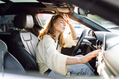 Canvas Print A young woman sits behind the wheel of a hot car