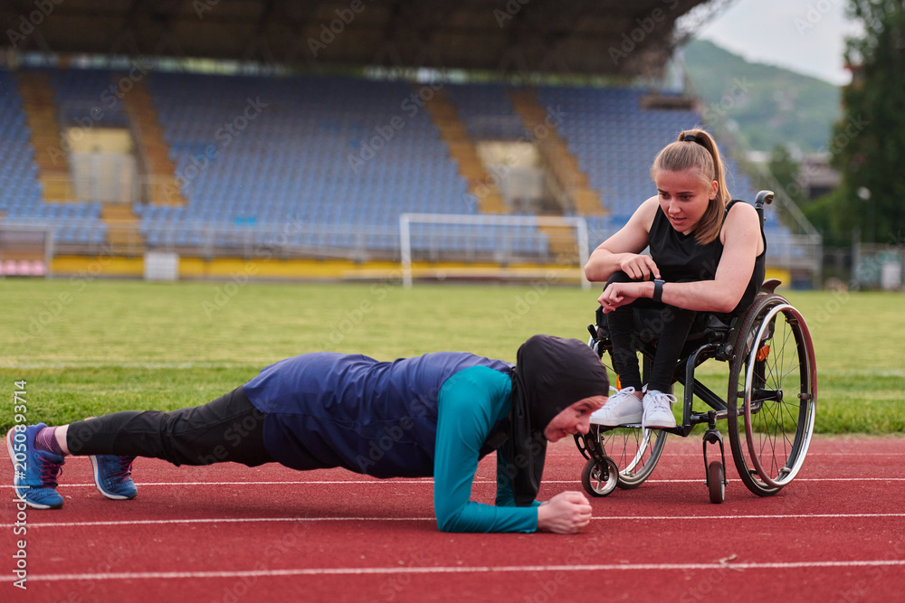 Naklejka premium Determined Wheelchair Athlete Coaching Friend During Outdoor Fitness Training On Track Stadium