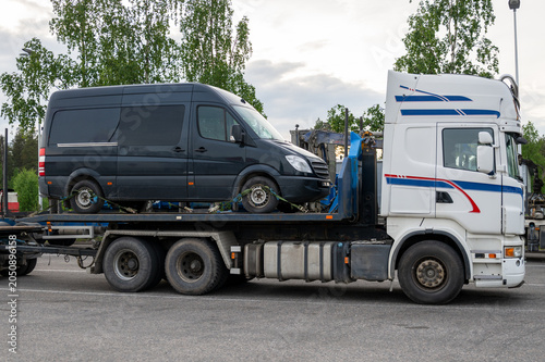 Cargo van transported on flatbed truck for vehicle logistics and road haulage