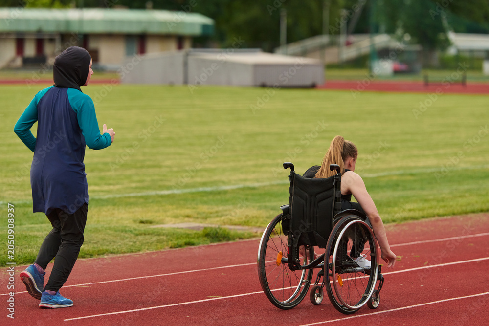 Naklejka premium Female Wheelchair Athlete Training On Track With Running Partner Wearing Hijab Inclusive Sports