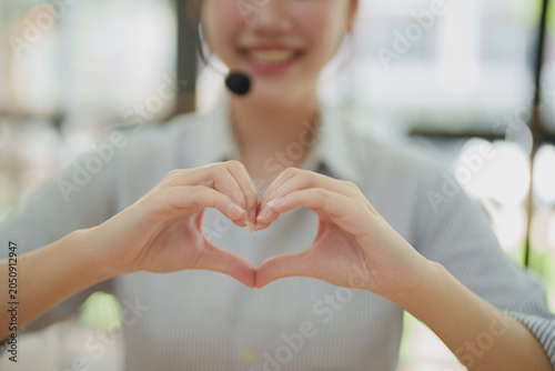Принти на полотні Call center employee wearing headset forming an adorable heart shape with hands,
