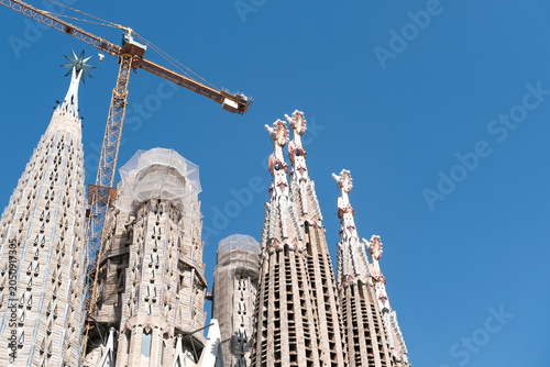 Barcelona, Spain: May 27, 2022. Detailed panoramic view of the top of the Antonio Gaudis Sagrada Familia cathedral and the construction crane. Bottom view against a clear blue sky. Copy space.