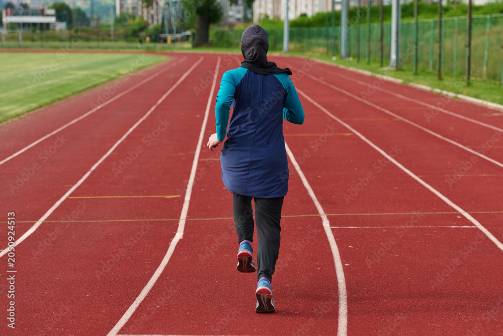 Fototapeta premium Woman in Hijab Running on Outdoor Track for Fitness and Endurance Training