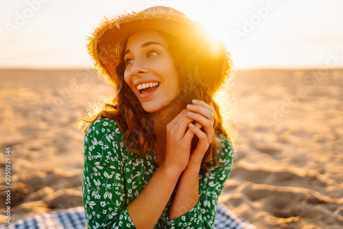 Fotografía A young woman sits on a beach mat in the sunset