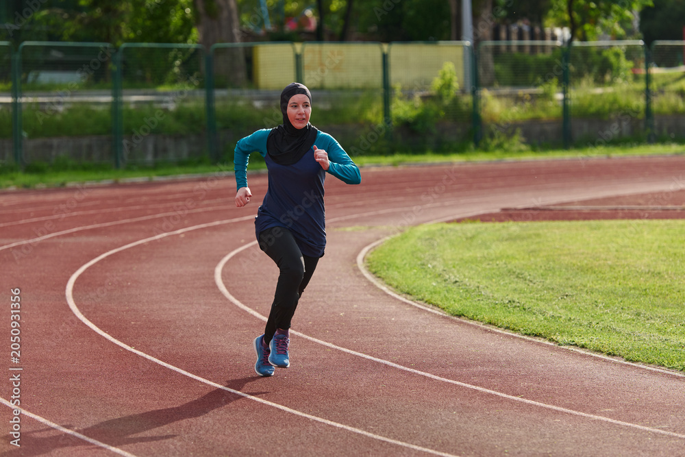 Obraz premium Muslim Woman Running on Outdoor Track in Hijab During Fitness Training and Athletic Practice