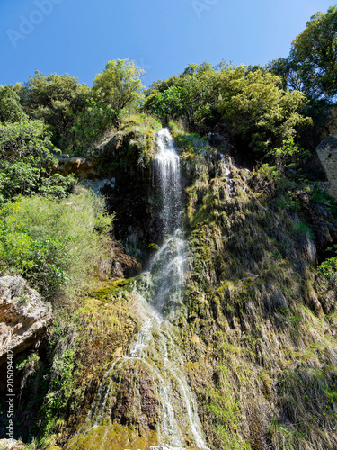 Impressive Villecroze waterfall in Provence in the Haut-Var region flows down a high tuf a cliff overlooking parks and flower gardens
