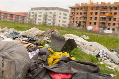 Foto A pile of discarded clothing, fabric and rags scattered on a grassy lot in front