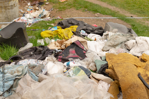 Quadro su tela A low-angle view of a large heap of discarded household items and textiles dumped on a patch of grass