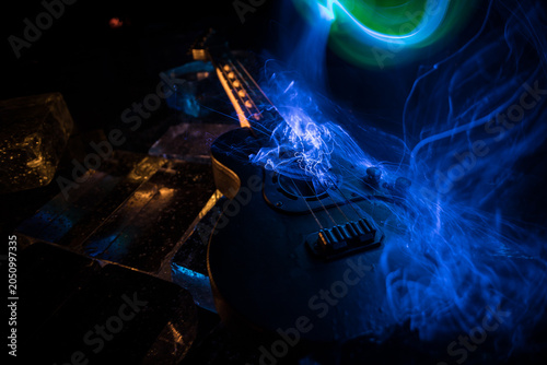 Music Concept: Guitar Miniature on a Dark Background with Vivid Light, Smoke, and Fire Effects. Golden electro guitar under a Dramatic Spotlight.