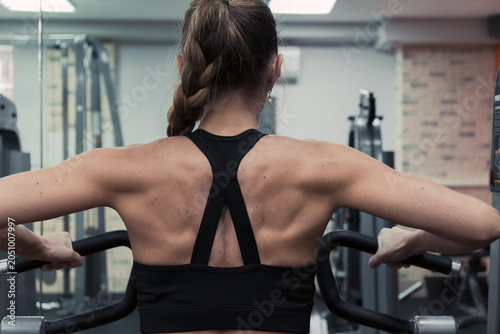 The trainer does exercises on various machines for the muscles of the arms, shoulders and back