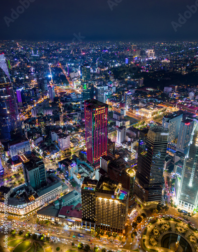 Fotografía Night aerial view of Ho Chi Minh City skyline with illuminated skyscrapers, busy streets, and vibrant urban lights in Vietnam's financial district