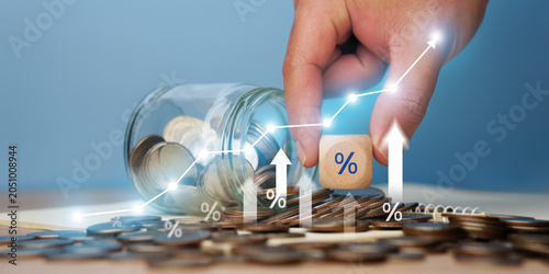 Schilderij op canvas A close-up image shows a businessman's hand placing a percentage stick onto a pile of coins with an upward-pointing arrow on a graph