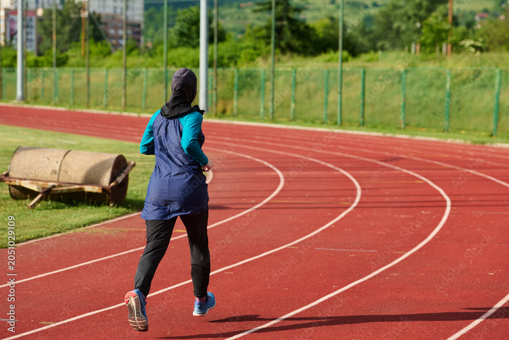 Obraz premium Muslim Woman Running On Outdoor Track Wearing Hijab Athletic Sportswear For Fitness Training