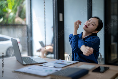 Asian businesswoman stretching during break at office desk