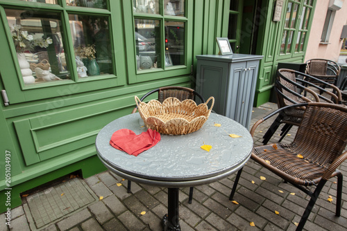 Outdoor table with woven basket and folded cloth at cafe in city during autumn morning