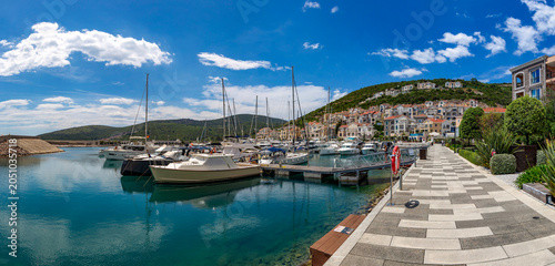 Breathtaking panoramic sweep of the exclusive Lustica Bay resort revealing its waterfront promenade, luxury yachts, and upscale stone residences. Montenegro