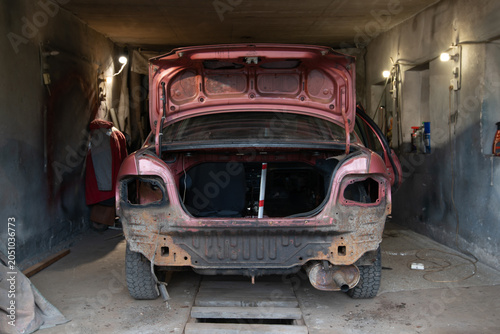 Old car being repaired in a workshop during daylight hours in a small garage