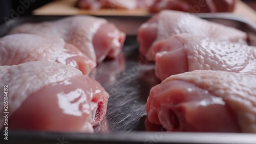 Close up shot of raw fresh chicken thighs arranged neatly on a metal tray in commercial kitchen, cooking meat food concept