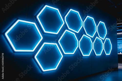 Bright blue glowing hexagonal light installations mounted on a dark modern interior wall, creating a futuristic decorative feature.