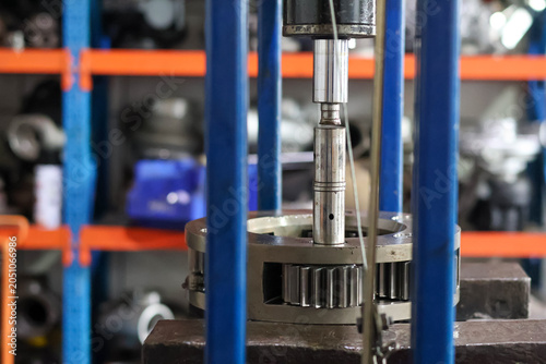 Bild auf Leinwand A close up view of a hydraulic press piston rod pushing a metal spindle pin to disassemble a heavy duty planetary gear mechanism